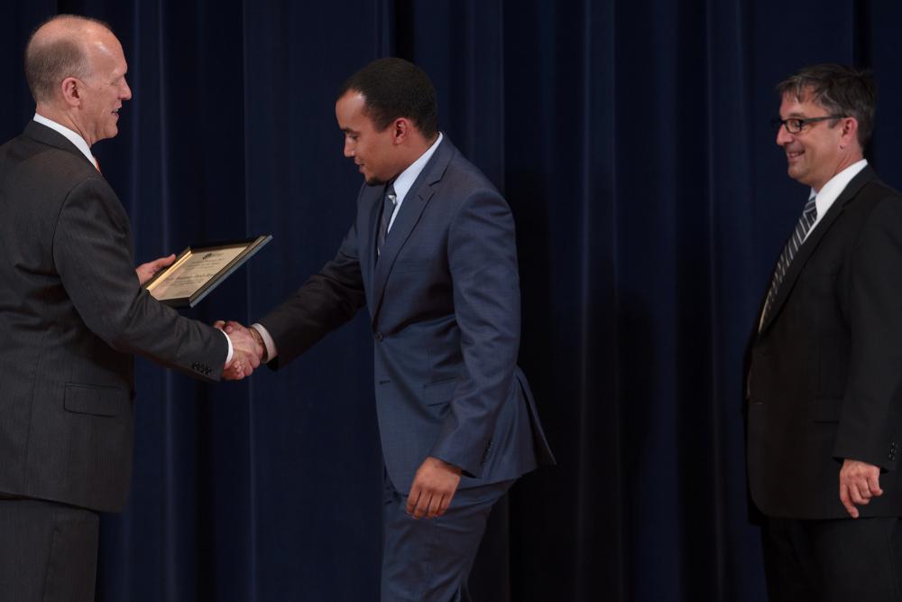 Doctor Potteiger shaking hands with an award recipient in a blue-grey suit